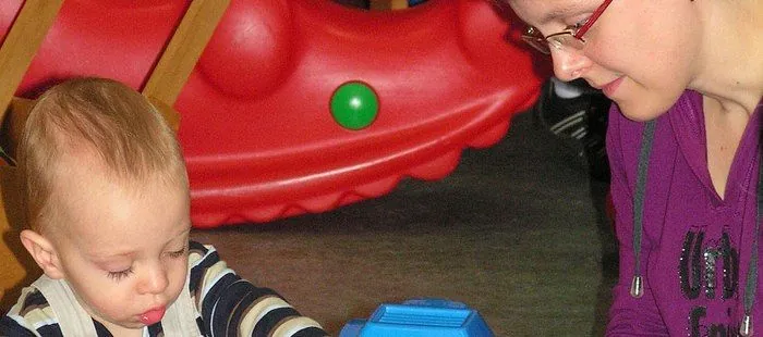 Ein Kleinkind und eine Frau schauen auf ein Spielzeug.
